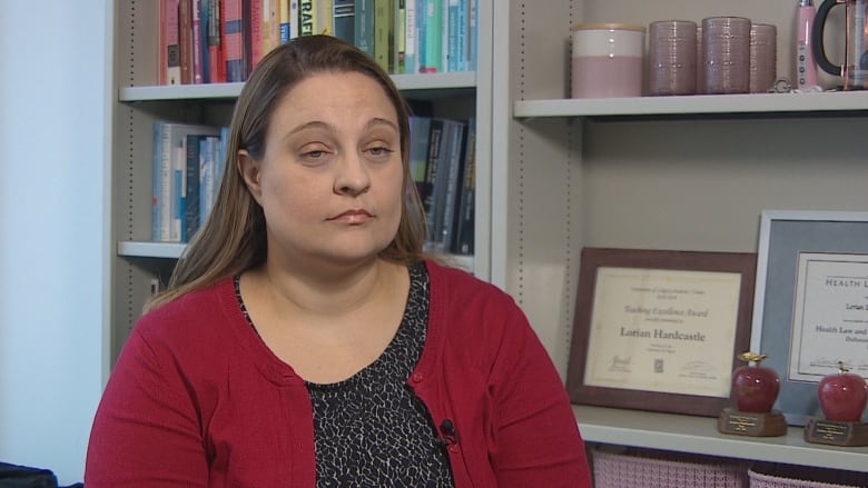 A woman in a red blazer sits in an office.