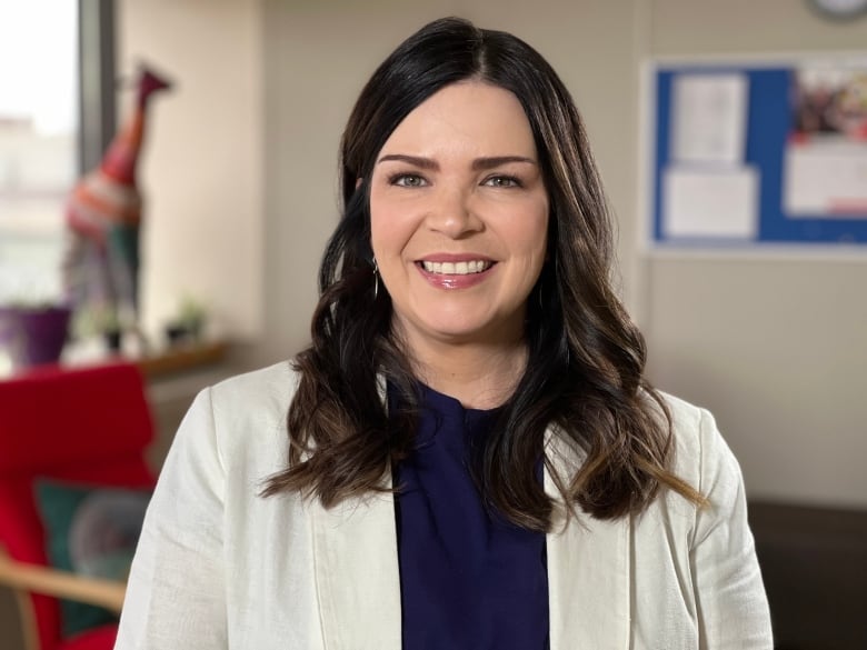 A smiling woman with dark hair is pictured in an office.