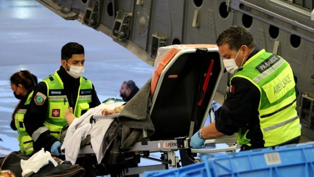 A patient is loaded onto an airplane to receive medical treatment