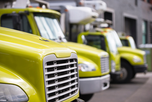 Middle class semi trucks with box trailers for moving and delivery services standing in row in warehouse dock waiting for customers