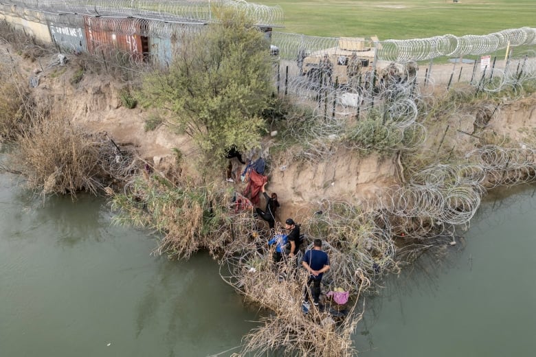 Aerial shot of people walking through razor wire