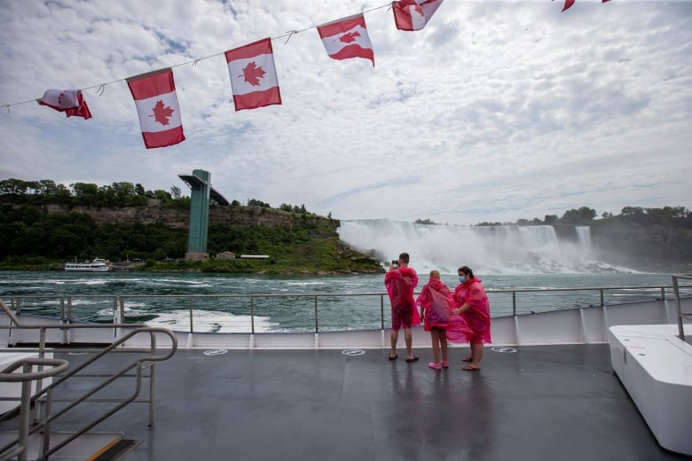 people in ponchos stand on boat deck