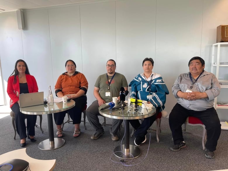 Five seated people look at the camera.