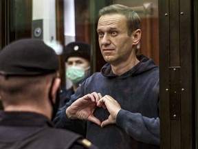 FILE - In this handout photo taken from video provided by the Moscow City Court on Feb. 2, 2021, Russian opposition leader Alexei Navalny shows a heart symbol while standing in a defendants' cage during a hearing in the Moscow City Court in Moscow, Russia. President Vladimir Putin says he supported an idea to release Navalny in a prisoner exchange just days before the man who was his biggest foe died. (Moscow City Court via AP, File)