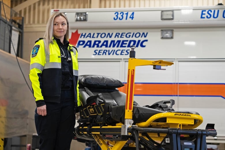 Longtime Halton Region paramedic Olena Campeau stands with a stretcher in front of an ambulance.