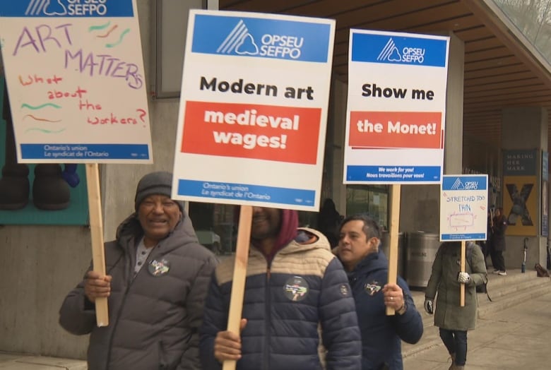 Signs read, "Art matters, what about the workers?" and "Modern art, medieval wages!" and "Show me the Monet!"