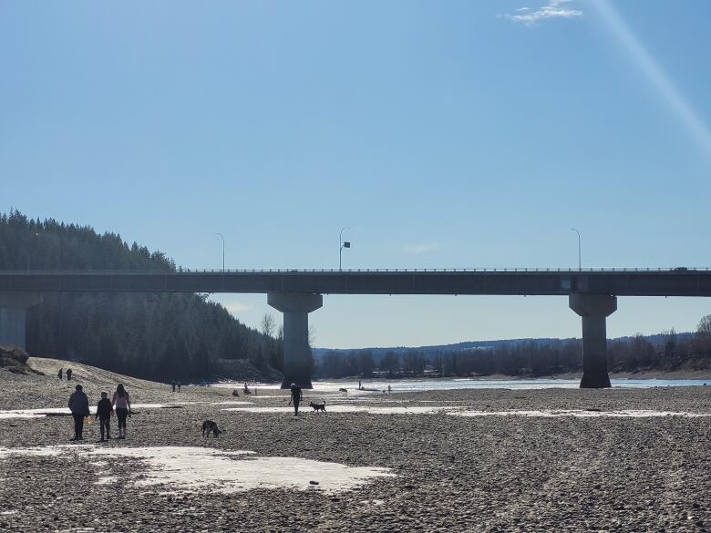 An empty dried-up riverbed with people walking.