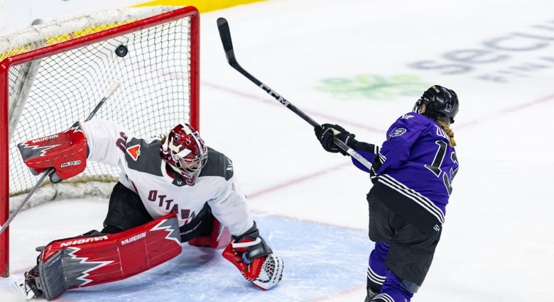 A female hockey player in a purple jersey, with Zumwinkle and the number 13 written on the back, shoots a puck over a goaltender and into the net.