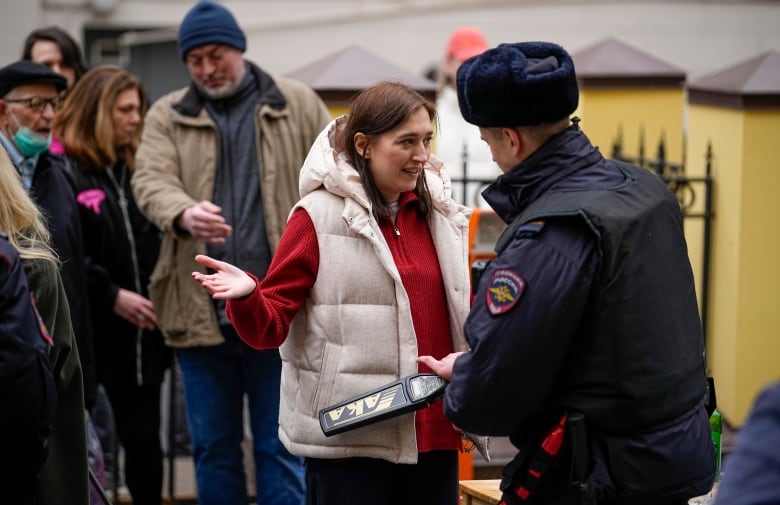 A police officer checks voter with a metal detector at a polling station in Moscow.