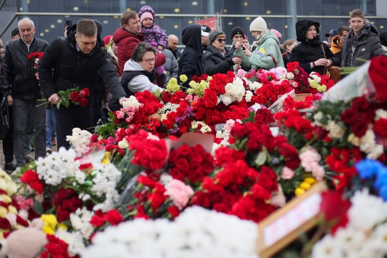 People place flowers and toys at the fence next to the Crocus City Hall music venue, on the western edge of Moscow.