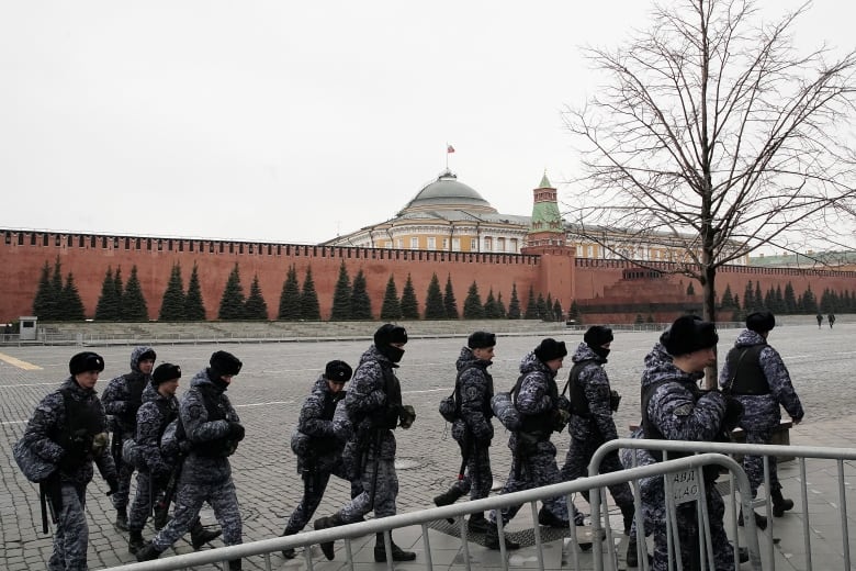 Russian National Guard officers walk past the Kremlin wall in Moscow.