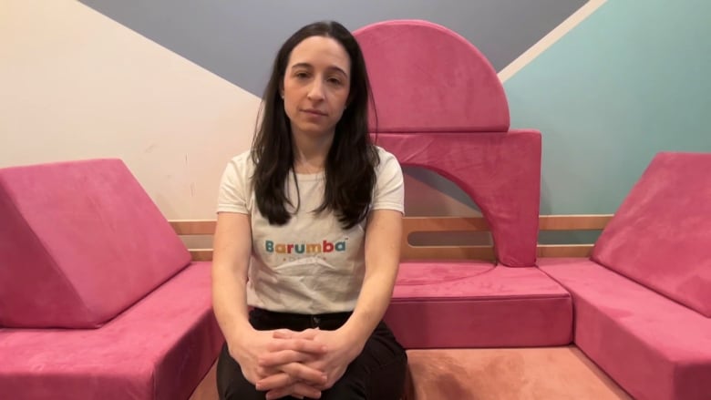 A woman is sitting on a pink toy couch.