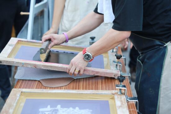 Close up of a person manually screen printing a shirt.