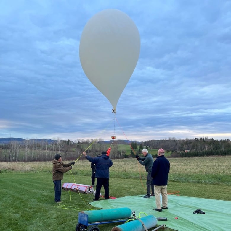 A group of men standing around a large weather balloon