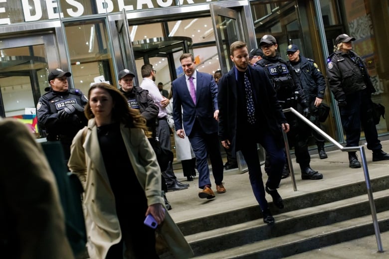 A person walks past a line of police officers standing guard at a building's entrance.