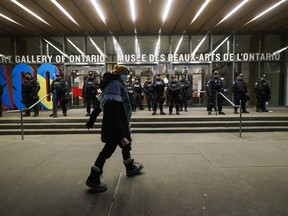 A protester walks as police line the entrance to the Art Gallery of Ontario, where a cancelled event for Canada's Prime Minister Justin Trudeau and Italy's Prime Minister Giorgia Meloni, was to take place, in Toronto, Saturday, Mar. 2, 2024.