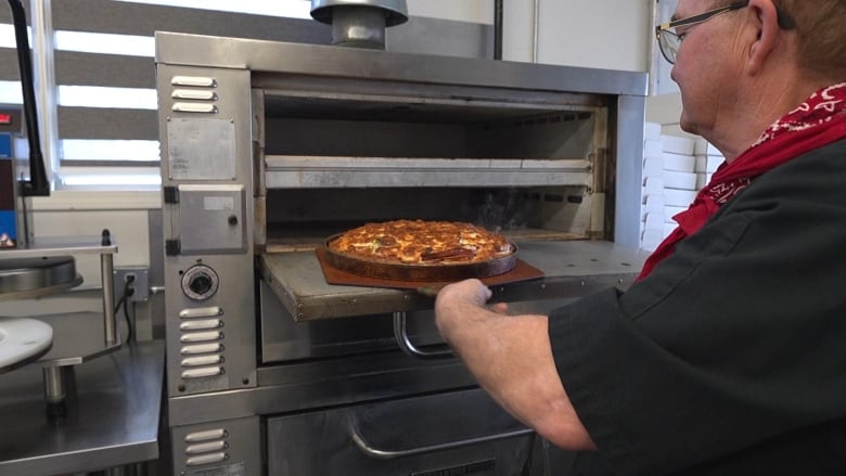 A hot Regina-style pizza is taken out of the oven.