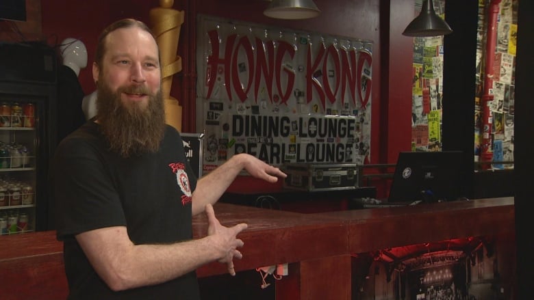 A man gestures toward bar. 