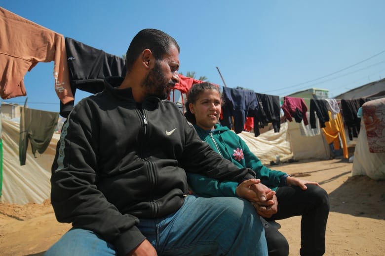 Alma Al Jarrour sits with her uncle Sami El Haddad.   He and wife say the orphaned girl will live with them from now on.  