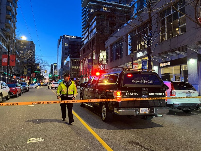 A police officer in a yellow jacket at a crime scene.