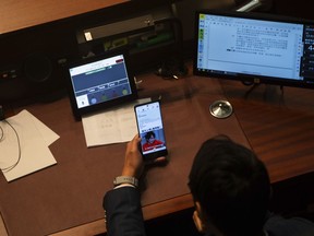 A lawmaker watches his phone during the second reading of the Basic Law Article 23 legislation at the Legislative Council in Hong Kong, Tuesday, March 19, 2024.