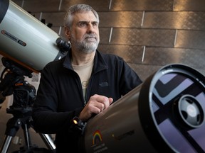 A white man poses in between two giant telescopes.