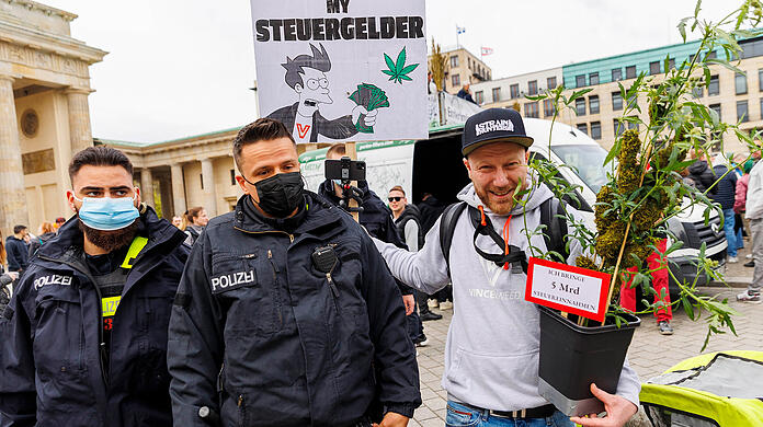 Dieser Demonstrant für die Cannabis-Legalisierung sieht die Situation ganz entspannt, die beiden Polizisten weniger.