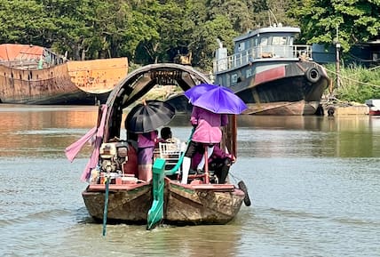 31.03.2024, Thailand, Ayutthaya: Menschen auf einem Boot auf dem Pa Sak River schützen sich bei Ayutthaya mit Sonnenschirmen vor der Sonneneinstrahlung.