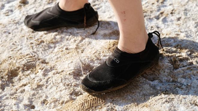 Freizeit: Ein Teilnehmer des Neujahrsschwimmen trägt am Ufer des Heidebades in Halle Neoprenschuhe.