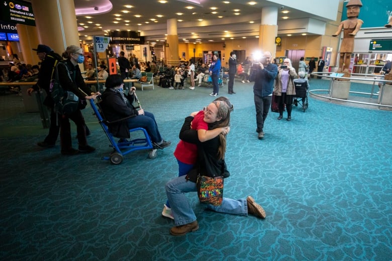 Two girls hug at the airport in Vancouver.