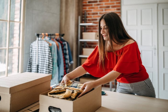 Woman boxing up some of her clothes.