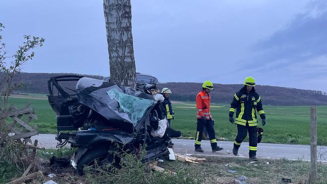 Landkreis Hameln-Pyrmont: Einsatzkräfte der Feuerwehr stehen neben einem zerstörten Auto.