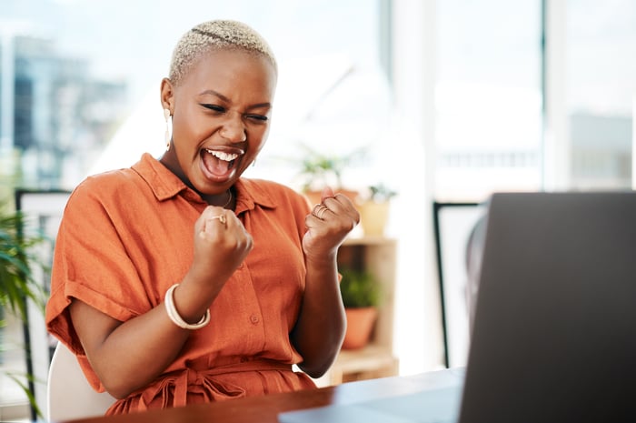 Person celebrating victory by computer. 