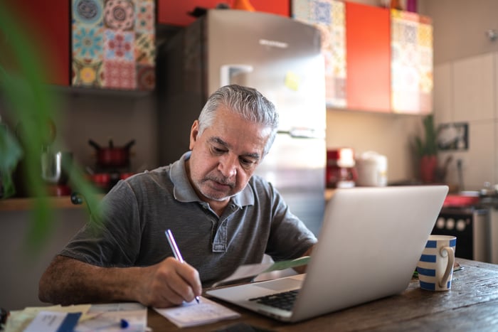 Person sitting in front of laptop and writing note.