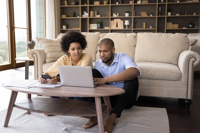 Two people in living room looking at laptop.