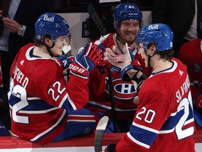 Cole Caufield smiles sitting on the bench and touching gloves with a smiling Juraj Slafkovsky