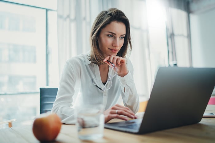 An investor studies something on a laptop in a home office.