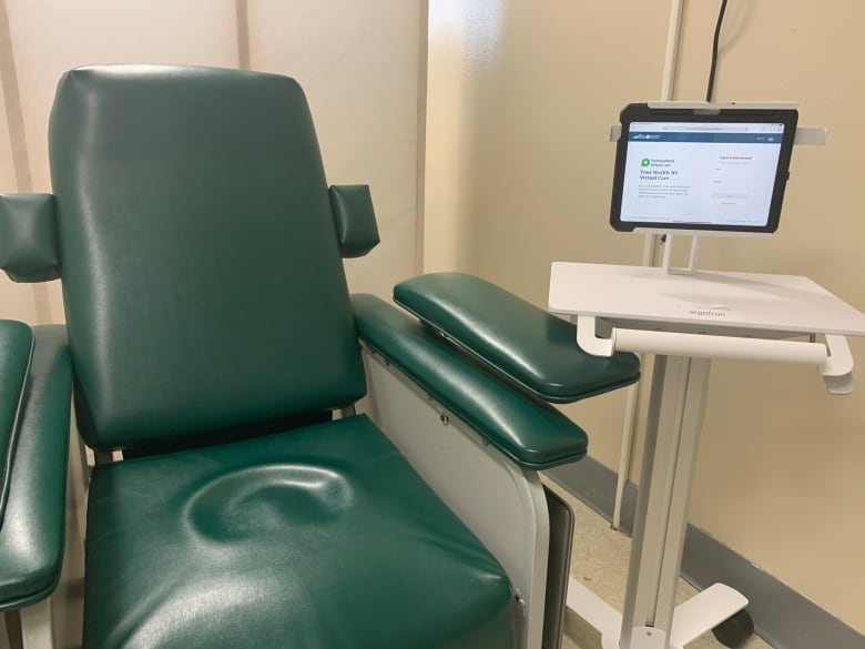 A large green padded chair beside an ipad in a holder.