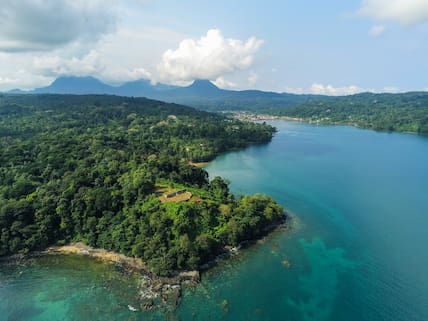 Blick auf die grün bewachsene Küste mit Bergen im Hintergrund von São Tomé & Príncipe, davor das klare Meer