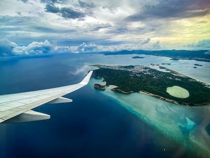 Blick aus dem Flugzeug auf die grüne Insel Mayotte mit einer türkisfarbenen Lagune inmitten des Ozeans