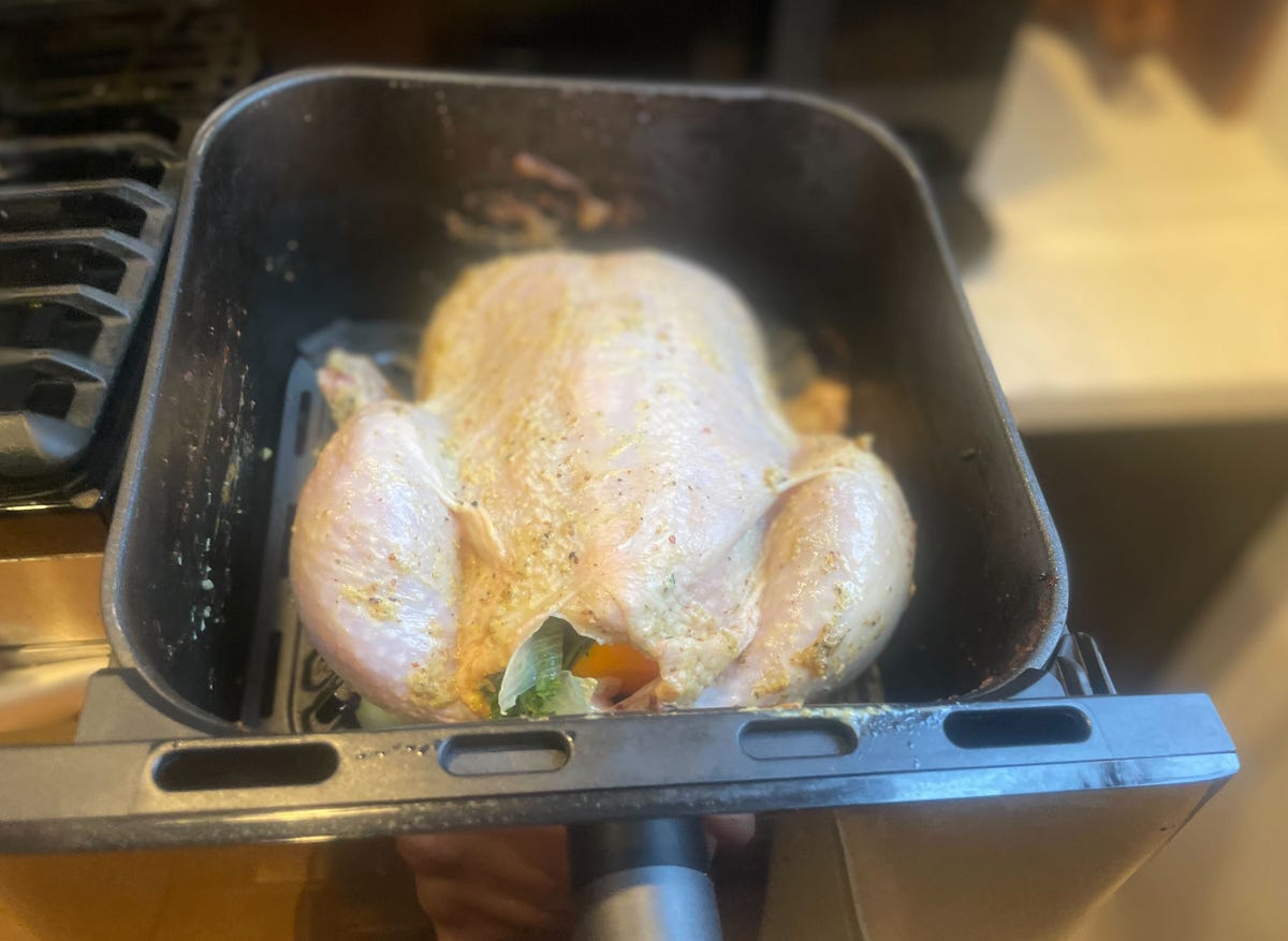 uncooked chicken rubbed with marinade in air fryer basket