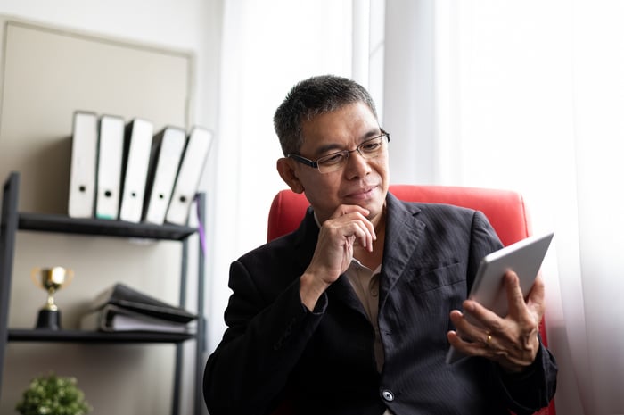 Thoughtful person looking at tablet in office.