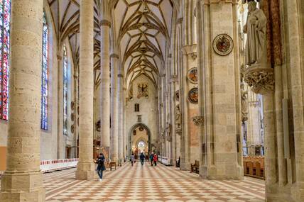 Blick in das Innere einer gotischen Kirche mit ein paar Besuchern.