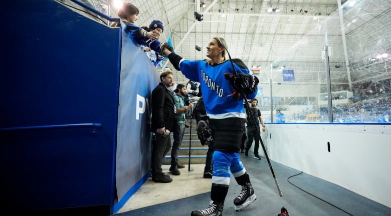 Women's hockey player greets fans before playing a hockey game. 