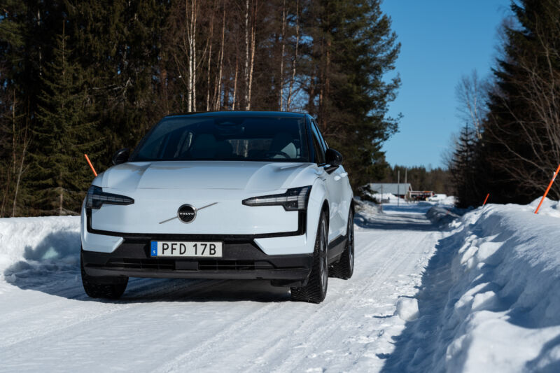 A grey Volvo EX30 parked on a snowy forest road