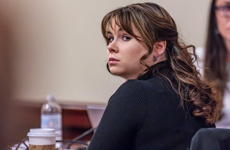 A woman sitting at a table looks over her shoulder. 