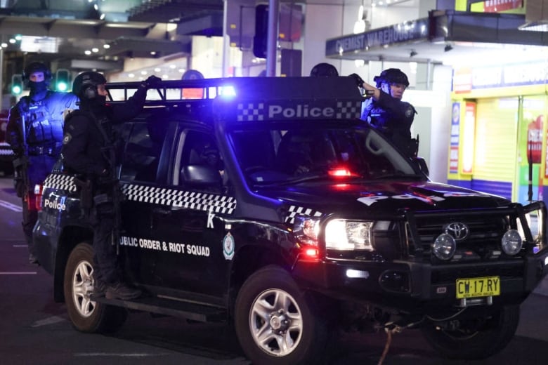 Members of police SWAT team hang on to a police vehicle.