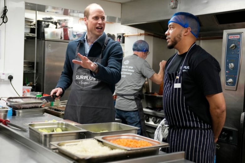 Two people talk in a commercial kitchen.