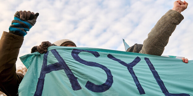 Zwei Protestierende halten ein Protestbanner hoch.