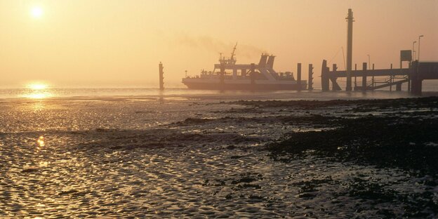 eine Fähre auf dem Meer im Sonnenuntergang bei dunstigem Licht